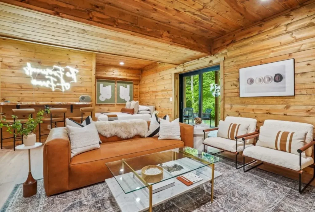 Open-plan living and sleeping space with leather couch, bar stools, and sliding doors inside a Hocking Hills A Frame Cabin.