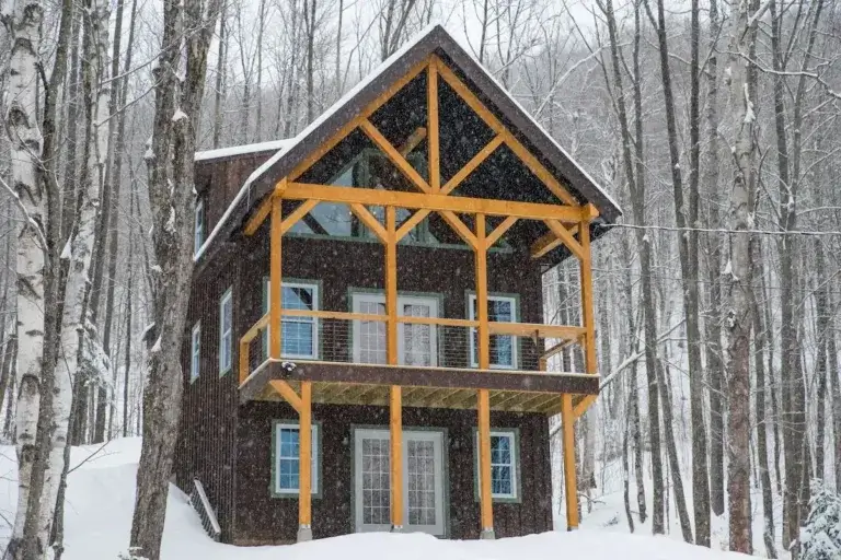 Multi-level timber frame cabin rental exterior surrounded by snowy winter forest in Jackson, New Hampshire