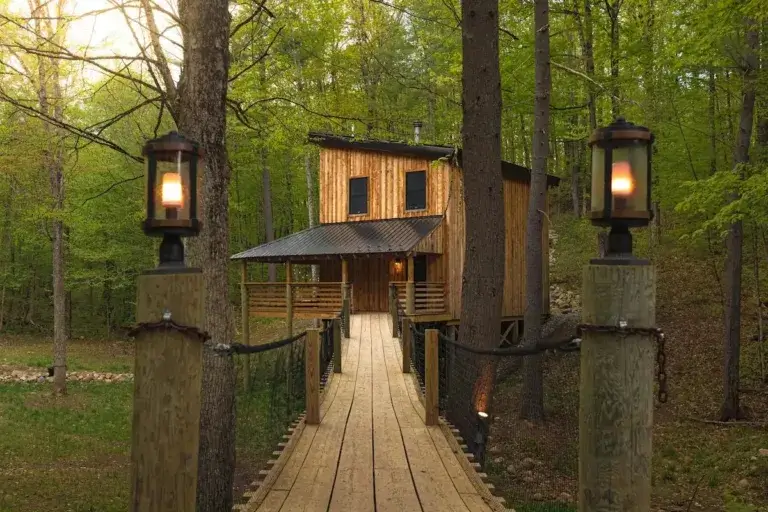 Entrance bridge with lanterns leading to Ultra-Luxury Treehouse cabin rental in Adirondack forest, Remsen, NY