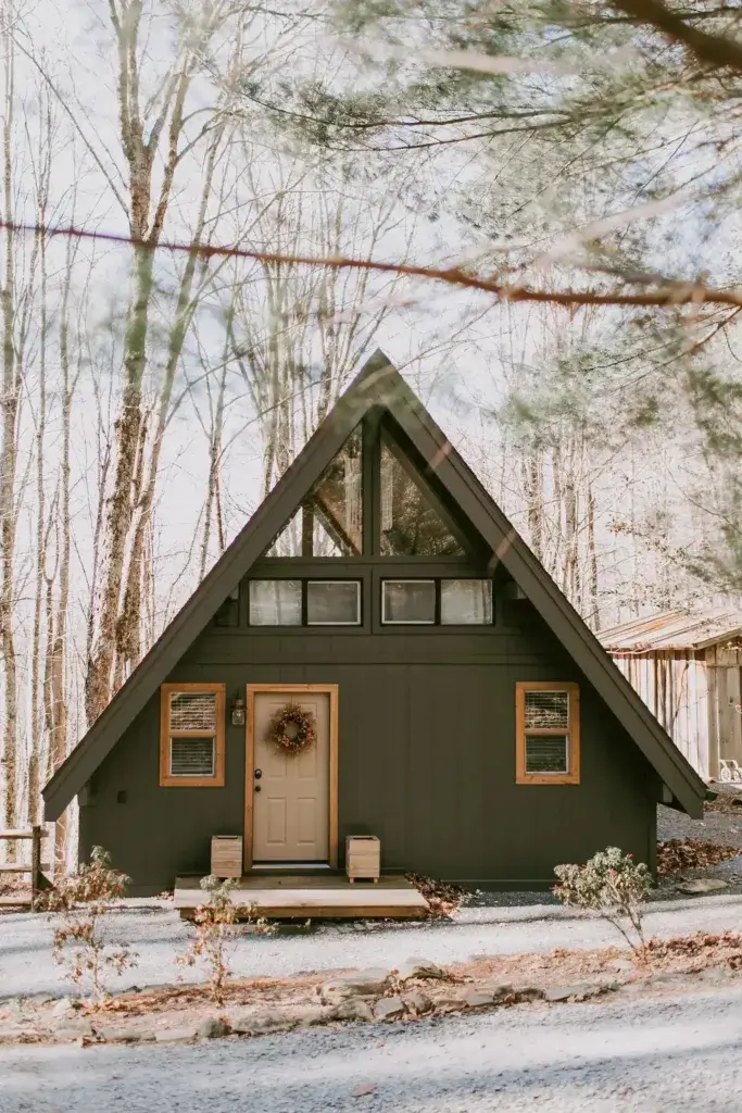 Front view of charming dark A-frame cabin rental nestled in woods near Boone, North Carolina