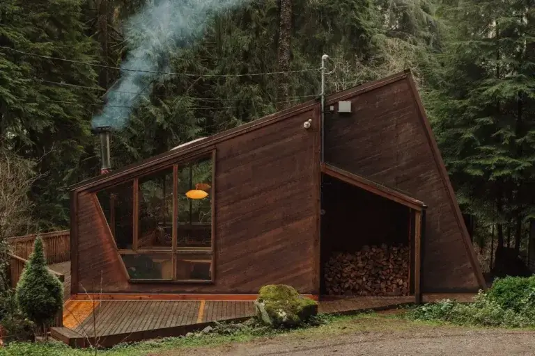 Unique angular dark wood Canyon Creek Cabin rental with smoking chimney in dense Washington forest, Granite Falls