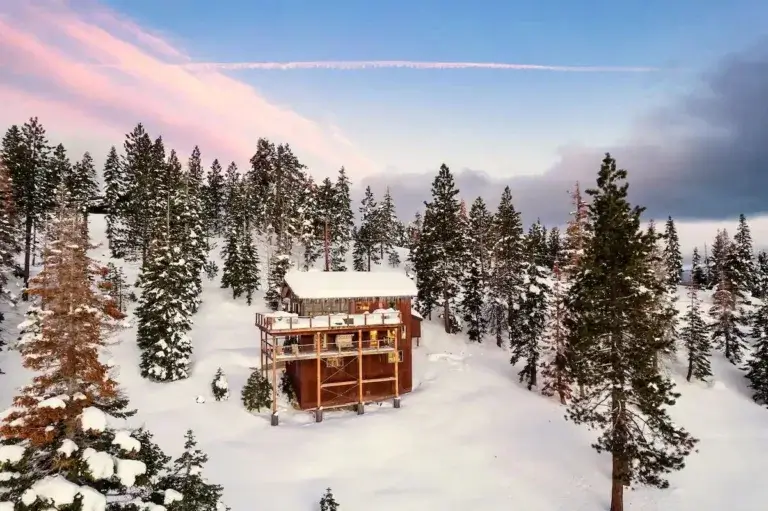 Heller Haus wooden mountain lodge cabin rental covered in snow amidst pine trees in Tahoma, Lake Tahoe, California