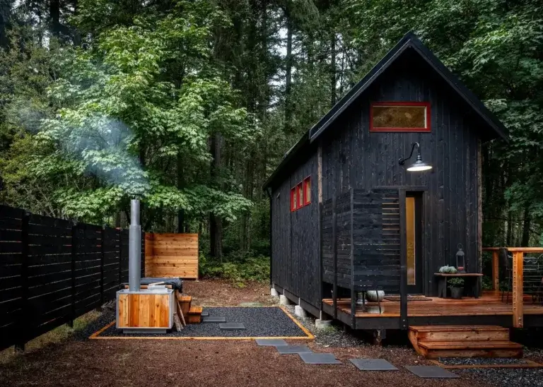 Modern dark Wolf Den tiny cabin rental with steaming wooden hot tub in Vashon Island forest, Washington