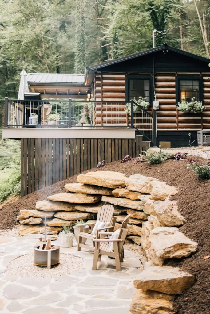 Waterfront Tiny Log Cabin in Airville, PA, featuring a stone patio with seating and a fire pit, below an elevated deck of the log-style cabin.
