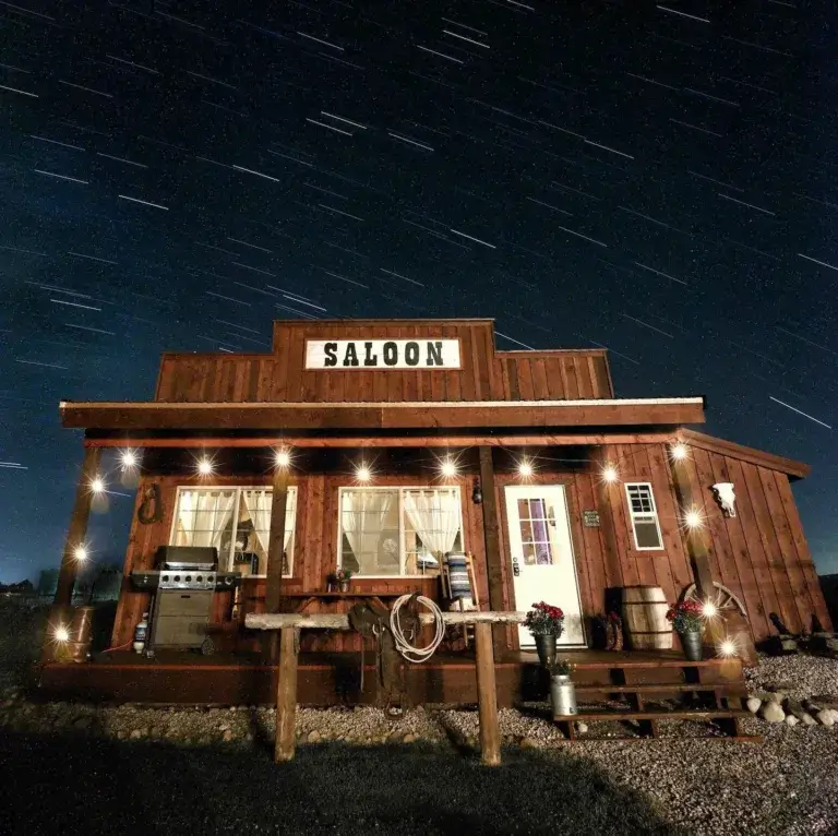 Unique Western Saloon themed cabin rental lit up at night with star trails overhead in Tetonia, Idaho