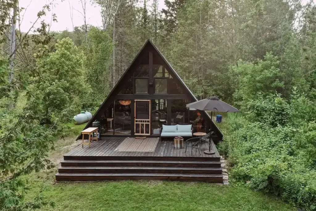Black Fernside A-frame cabin rental with glass front and large wooden deck in Michigan woods, Indian River