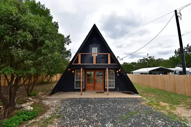 Black A-frame home rental with wood doors and balcony near Canyon Lake, Texas