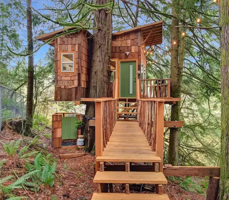 Rustic Cedar Falls Treehouse rental with cedar shake siding viewed from entrance bridge in North Bend, Washington forest