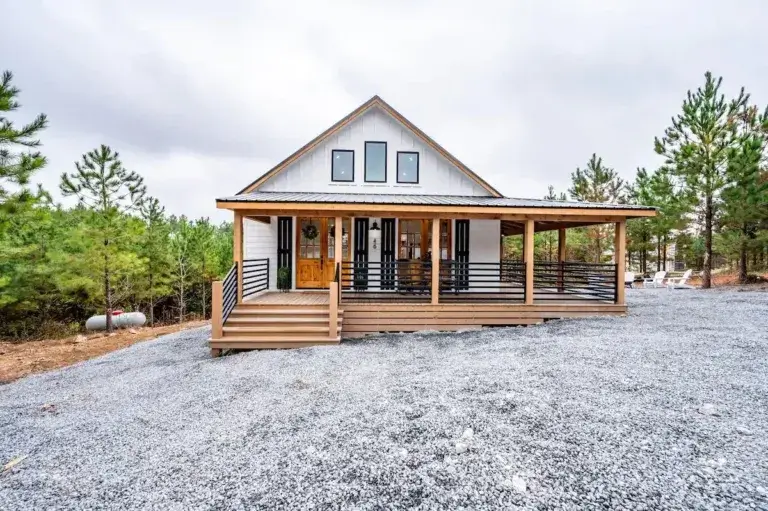 Modern white farmhouse cabin rental 'S'mores + Snores' with large wrap-around deck in Broken Bow, Oklahoma