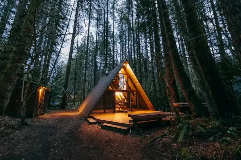 Sky Haus A-frame cabin rental with glowing glass front and deck nestled deep in Skykomish, Washington forest