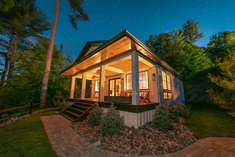 Upscale Adirondack Luxury Lakefront Villa rental lit up at night with welcoming porch under starry sky, Remsen, NY