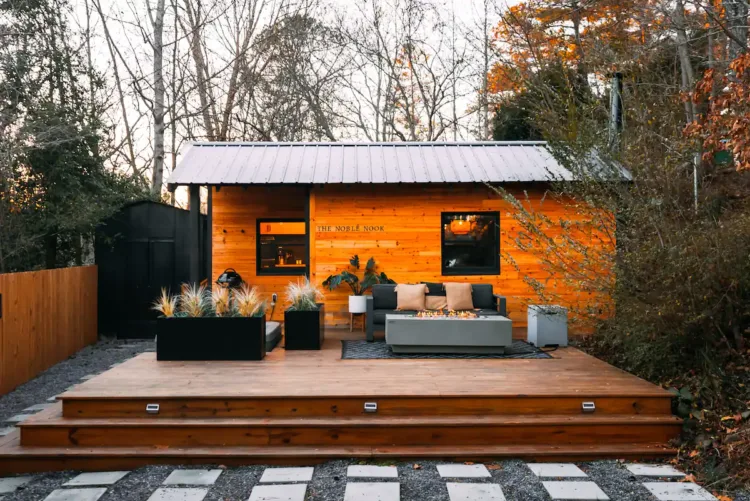 The Noble Nook tiny home near Asheville, featuring a stylish wooden deck with outdoor sofa and fire pit, an example from our list of best tiny home vacation rentals.