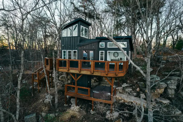 Luxury Sassafras Treehouse rental in Rising Fawn Georgia with dark siding, glass-railed decks, and hot tub on Lookout Mountain.