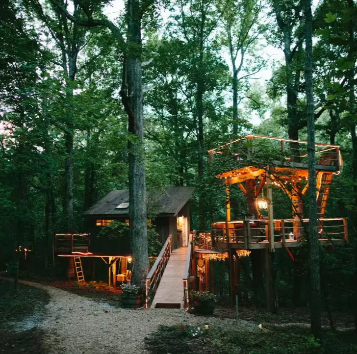 Expansive Majestic Treehouse complex in Walhalla South Carolina, illuminated with warm lights at dusk, featuring multiple structures and walkways.