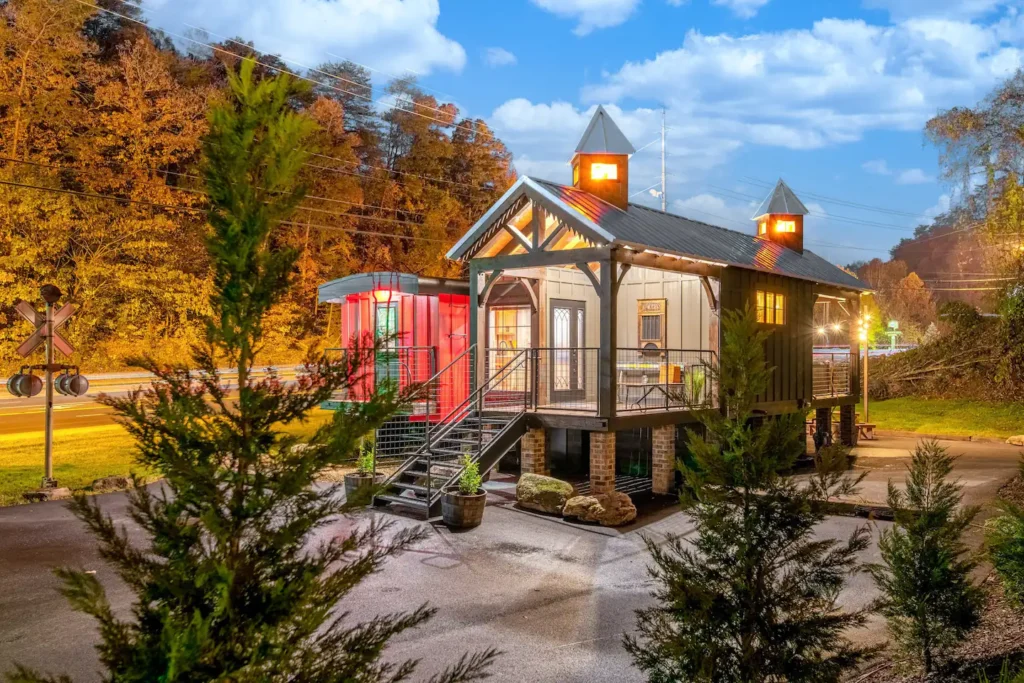 Unique shipping container home design of 'Smoky Mountain Station' in Pigeon Forge, blending a classic train station aesthetic with a modern red container.