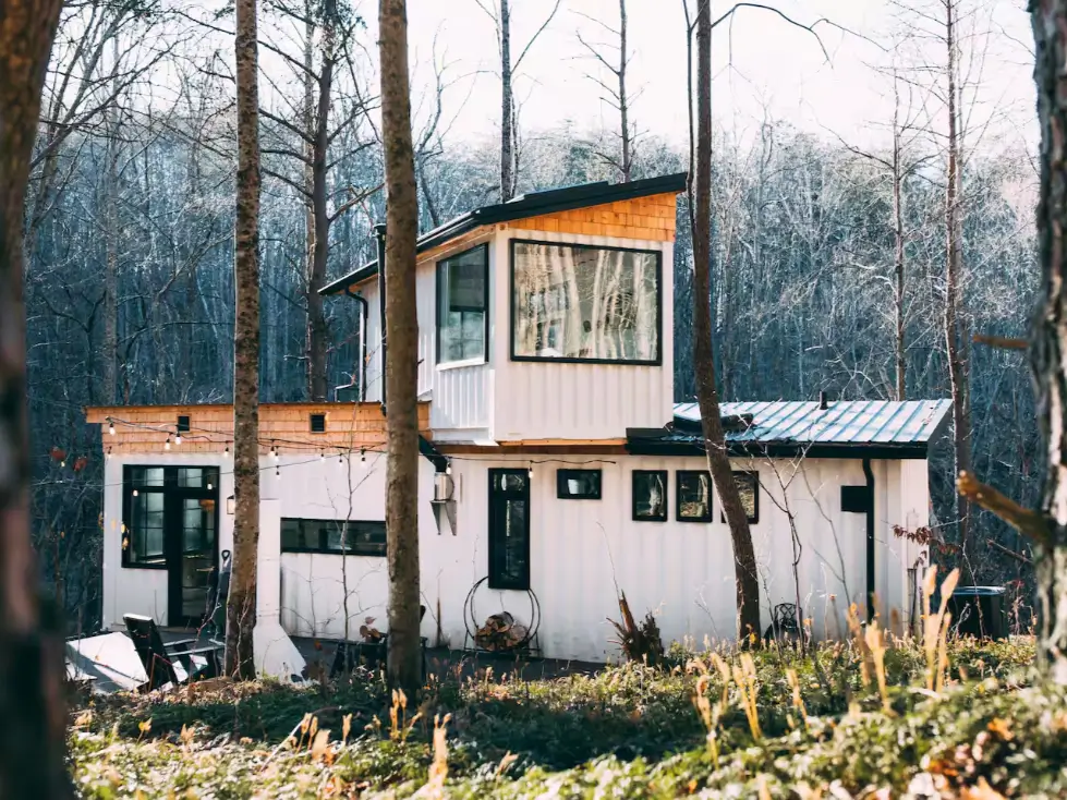 The BoHo Box Hop shipping container home design in Hocking Hills, showcasing a white exterior with natural wood shingle accents for a modern bohemian style in the woods.
