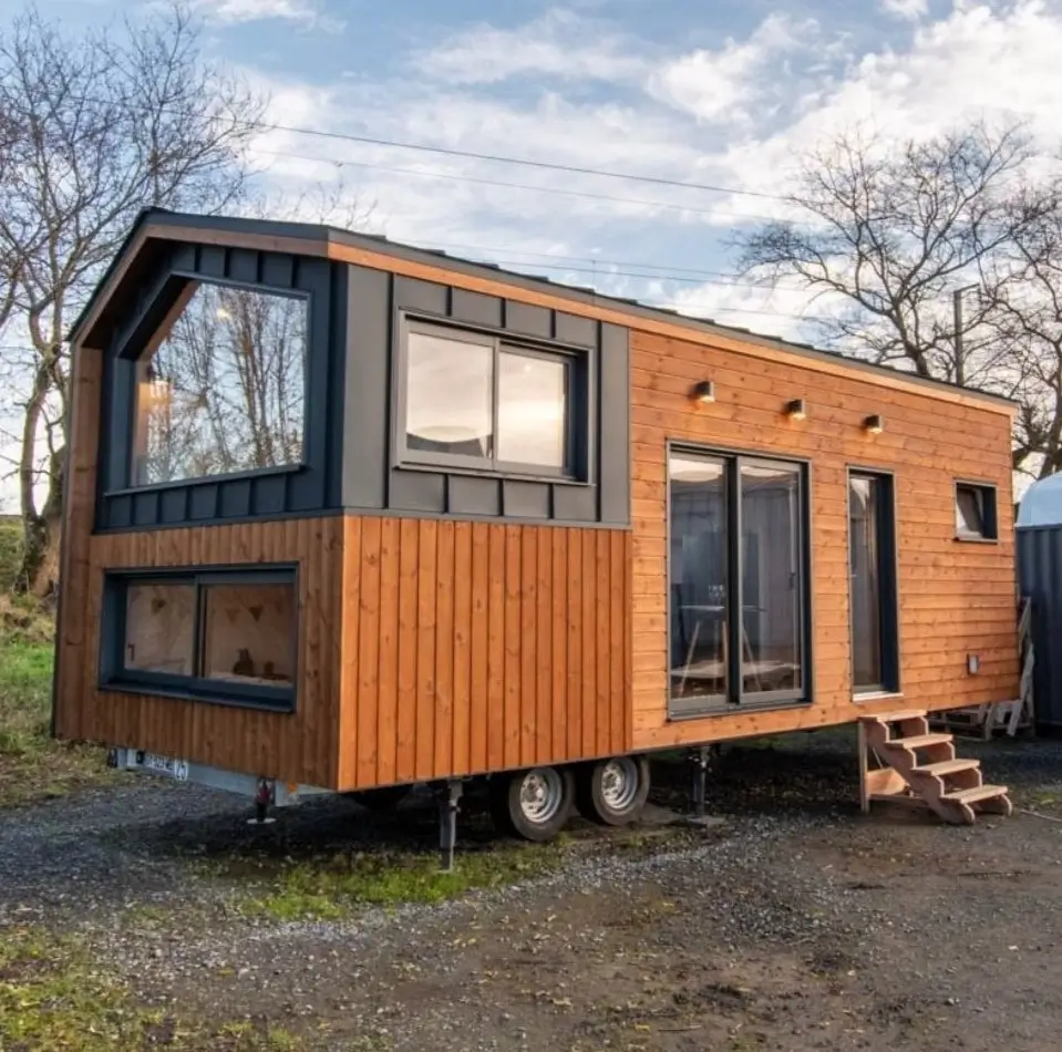 A modern tiny house on wheels in Ohio with natural wood siding and black metal trim.