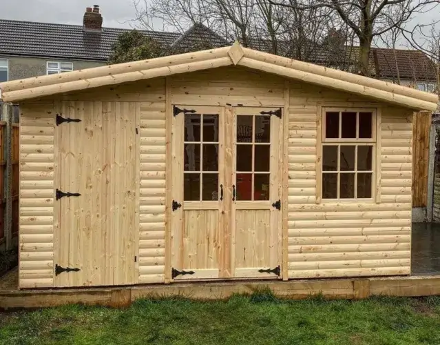 A classic shed log cabin made of natural pine wood, featuring double glass-paned doors and a side storage unit.