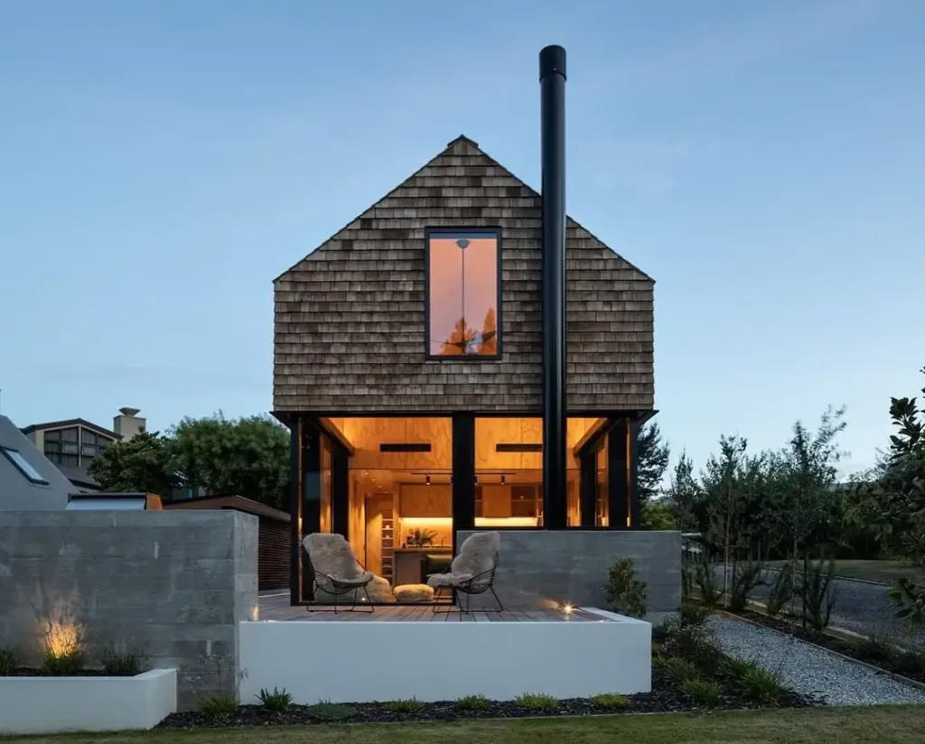Scandinavian house style exterior with natural cedar shingles and a tall black chimney.