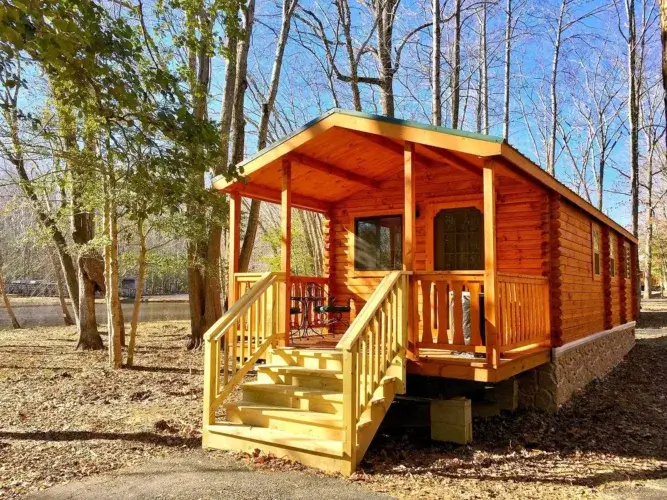 The 400sqft Lakeview log cabin kit in a wooded setting with sunlight filtering through trees.
