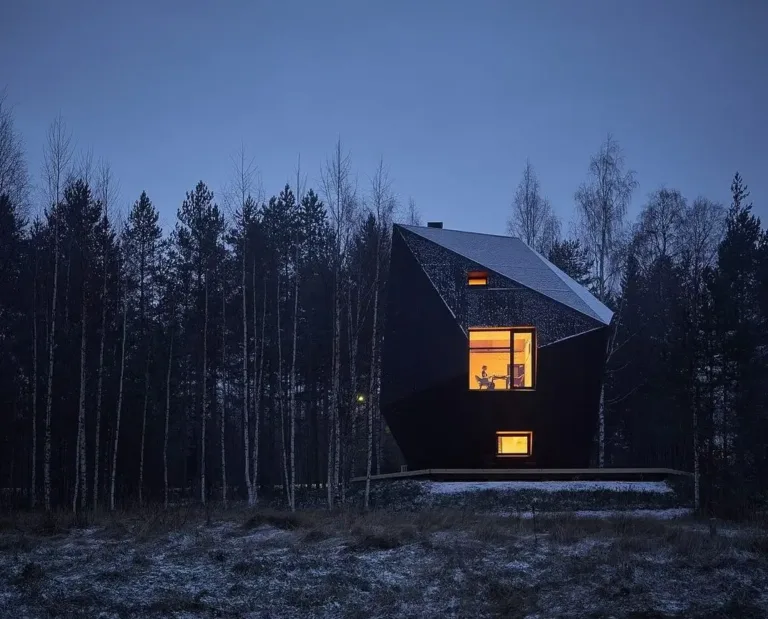 Meteorite Cabin in Finland, a dramatic dark angular structure in a forest at twilight, showcasing bold modern Scandinavian-inspired design.