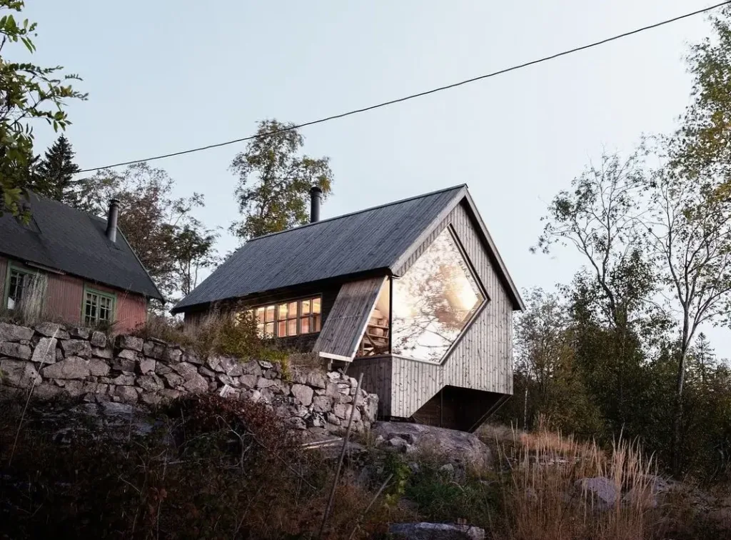 Cabin Nordmarka in Oslo, a dark-clad wooden cabin with a unique diamond-shaped window, blending traditional Nordic elements with modern Scandinavian design.