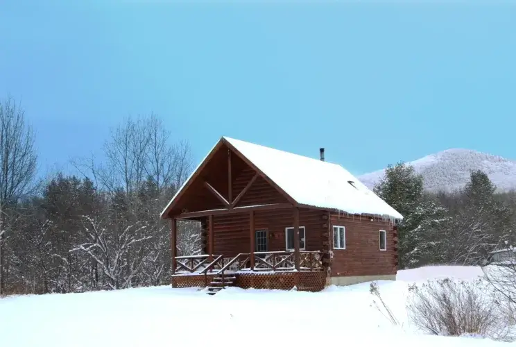 The Explorer log cabin kit in a pristine snowfield with a mountain visible in the distance.