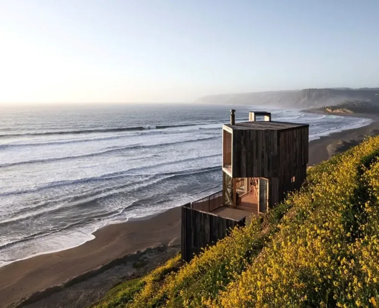 La Loica and La Tagua Cabins in Chile, rustic dark-wood structures on a cliffside, offering stunning ocean views and showcasing Scandinavian-inspired coastal design.