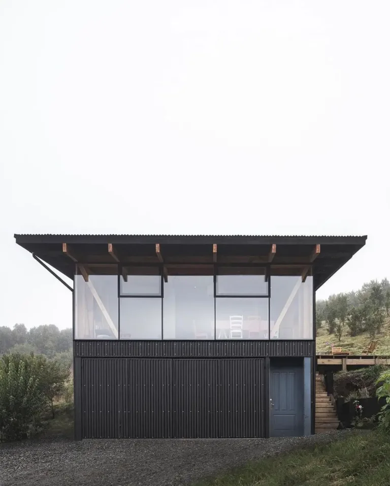 Scandinavian-inspired cabin exterior with a mix of natural wood and dark metal siding, set in a natural landscape.