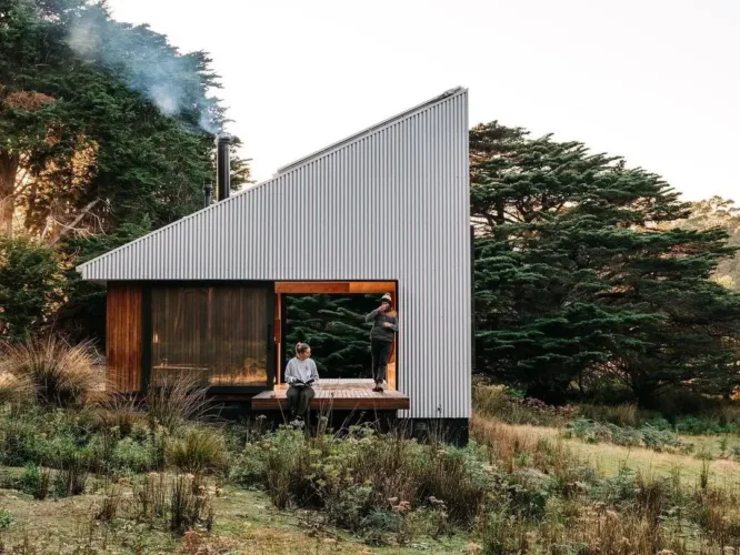 Remote off-grid cabin with light wood and dark metal exterior, designed to blend into the natural Tasmanian environment.