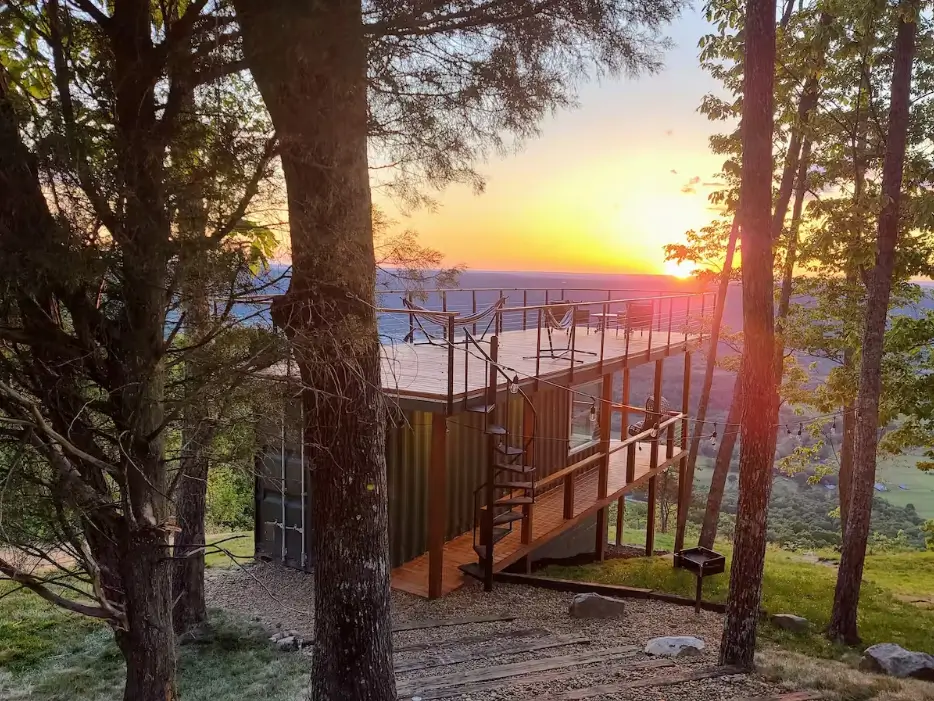 Cloud 9 shipping container home design in Rising Fawn, GA, highlighting a rooftop deck with hammock and spiral staircase for accessing stunning Lookout Mountain views.