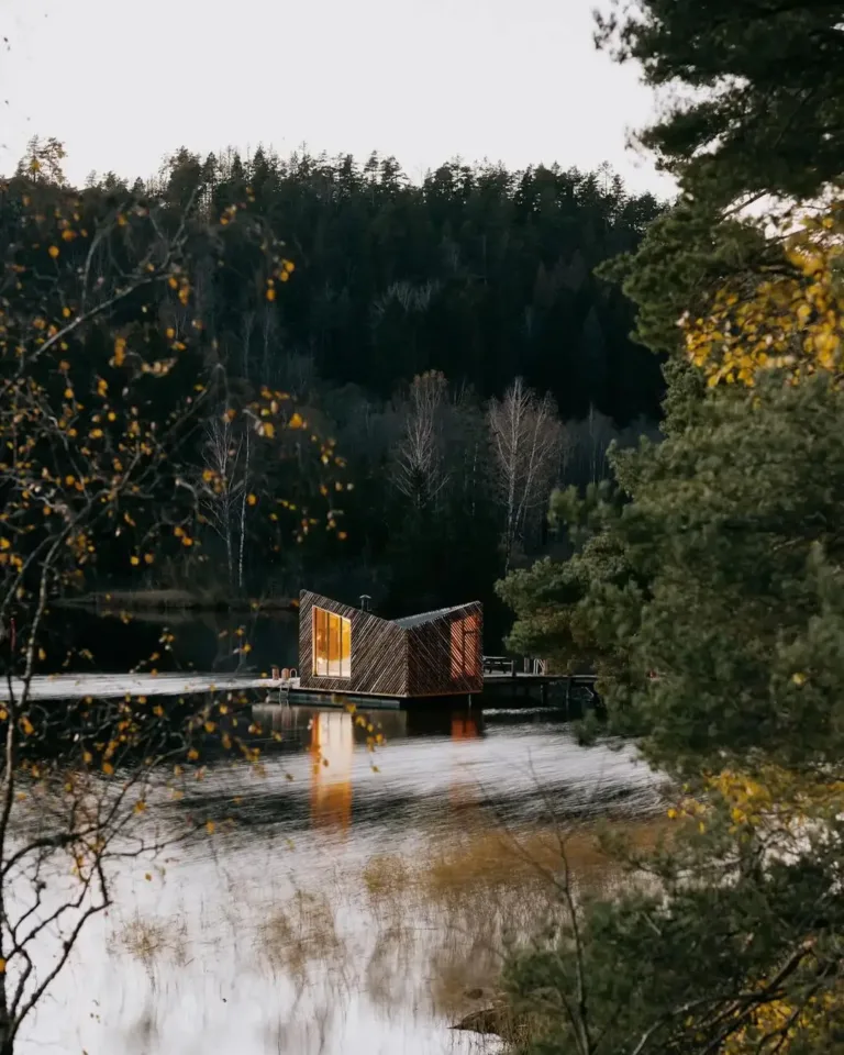 Unique floating cabin with a rough wood exterior and a distinctive angled roof pointing towards the water.