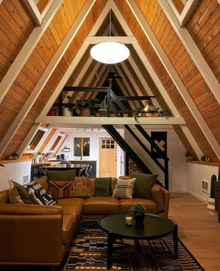 Cozy simple A-frame house interior featuring timber-clad ceiling and a large tan corner sectional sofa.