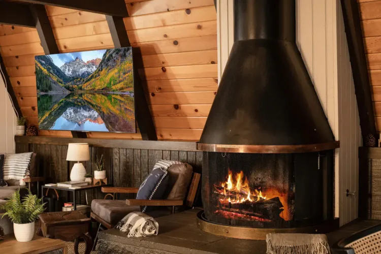 Stylish A-frame house interior with a freestanding black conical fireplace featuring a distinctive copper band.