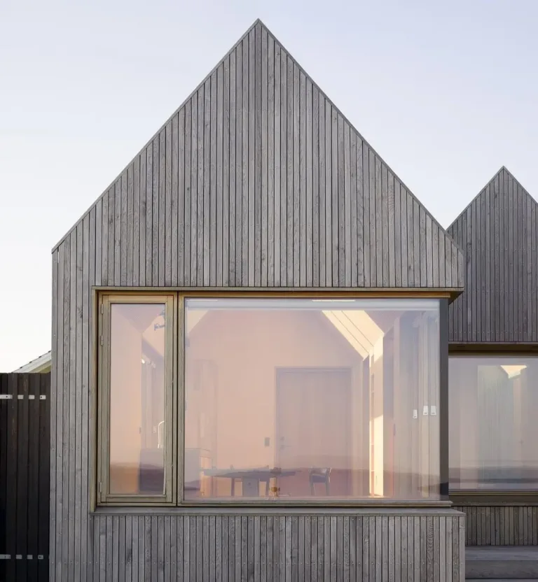 Cluster of charming Danish summer cottages with pitched roofs and natural wood siding, creating outdoor nooks.
