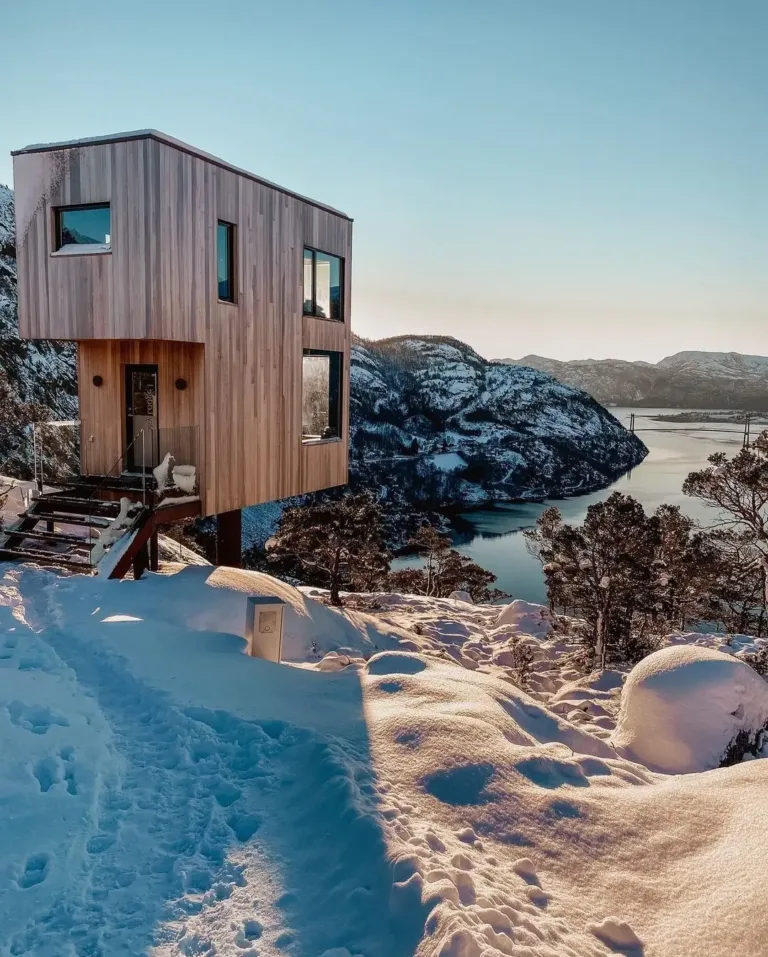 The Bolder Sky Lodge in Norway, a modern light-wood cabin on a snowy mountain, offering spectacular fjord views, embodying luxury Scandinavian design.