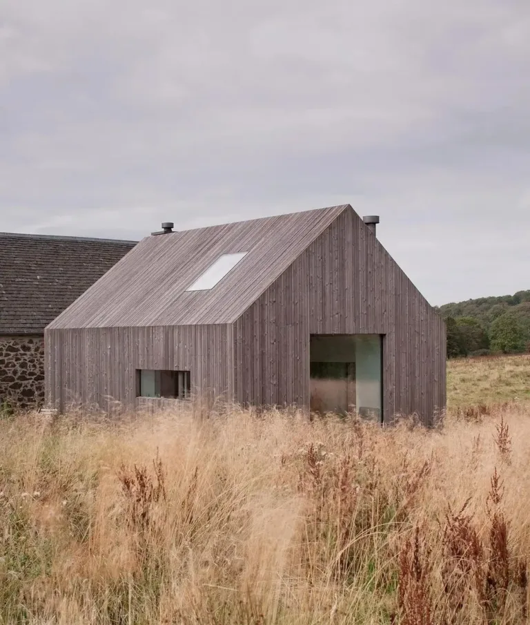 Unique house integrating an old stone ruin with new timber sections and a glass hallway.