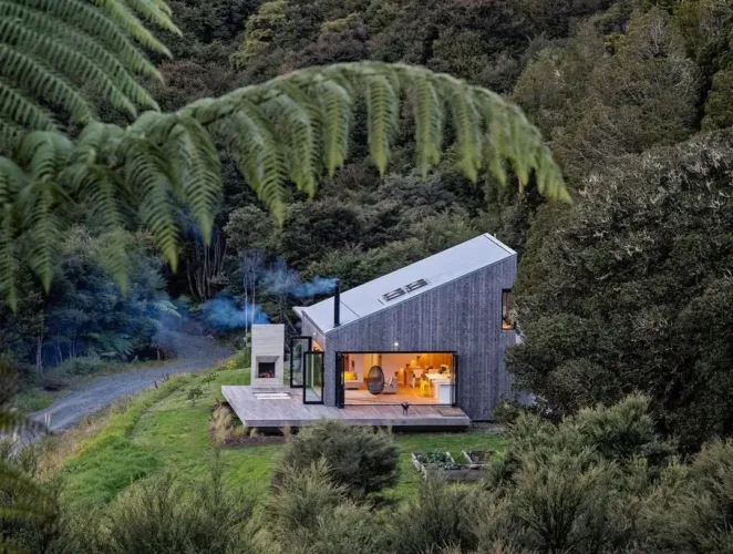 Contemporary Scandinavian home exterior with a dark, angled facade and a bright, open interior visible.