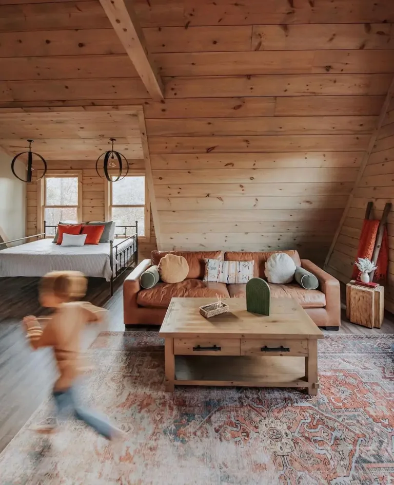 Rustic chalet-style A-frame house interior with wood paneling, showing combined living and sleeping areas.