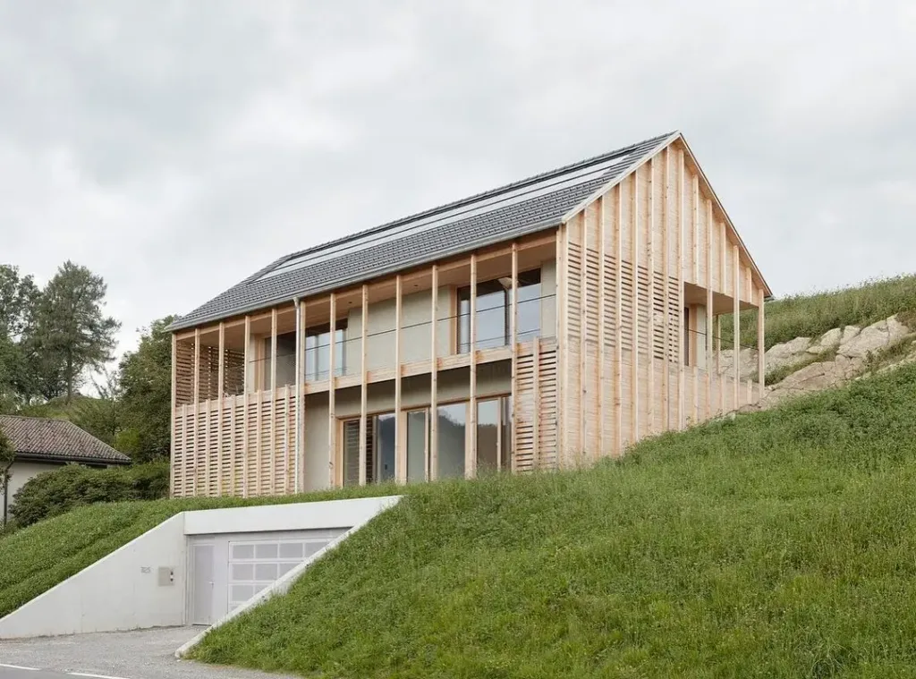 Modern Austrian house with a simple pitched roof and a covered terrace, blending traditional farmhouse style with contemporary design.