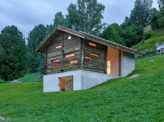 Transformed barn exterior in Switzerland, showcasing a blend of traditional stone and modern wooden sections.