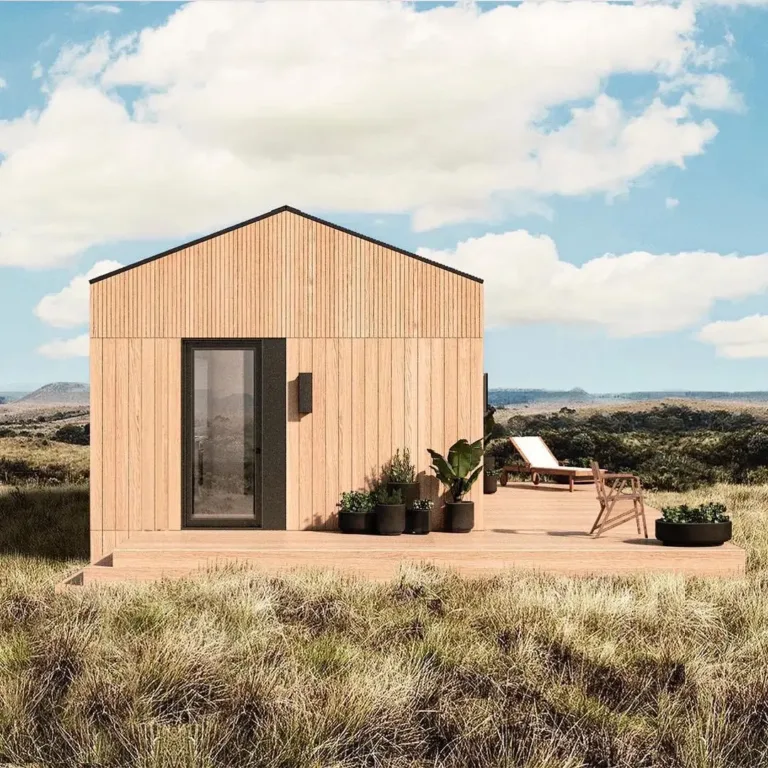 Compact prefabricated house exterior with a clean design and a large folding glass wall.