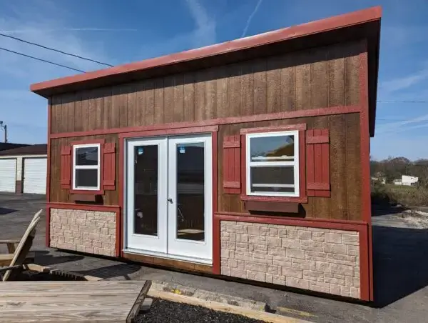 A 12x20 Skillion tiny home shell with brown wood siding, red shutters, and a single-slope roof.