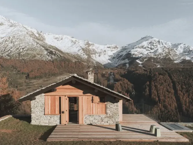 Renovated mountain cabin exterior with new, expansive windows designed to open wide and capture alpine views.