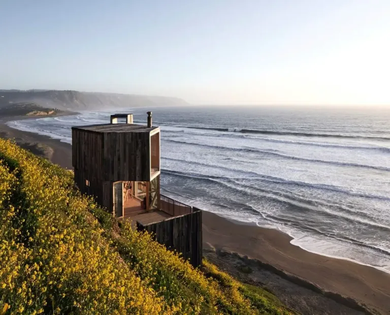 Small wooden cabin exterior perched on a hill overlooking the ocean, with a clever loft design for maximizing space.