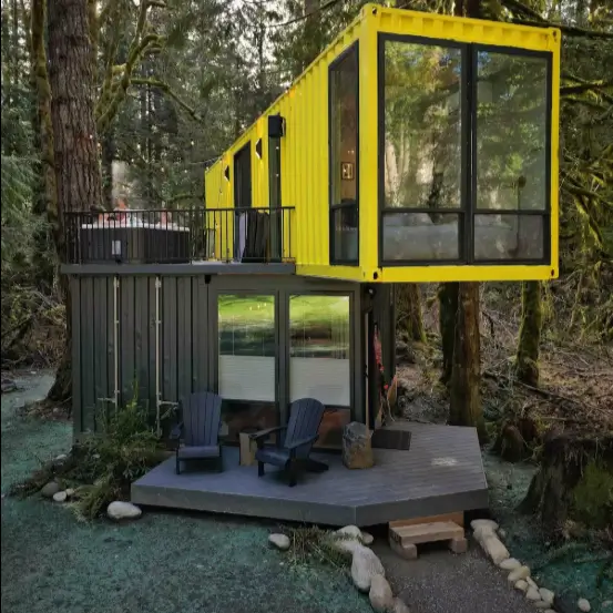 Striking shipping container home design of The Sea Containers in Index, WA, with a bright yellow upper container dramatically cantilevered over a dark grey base, featuring a hot tub and forest views.