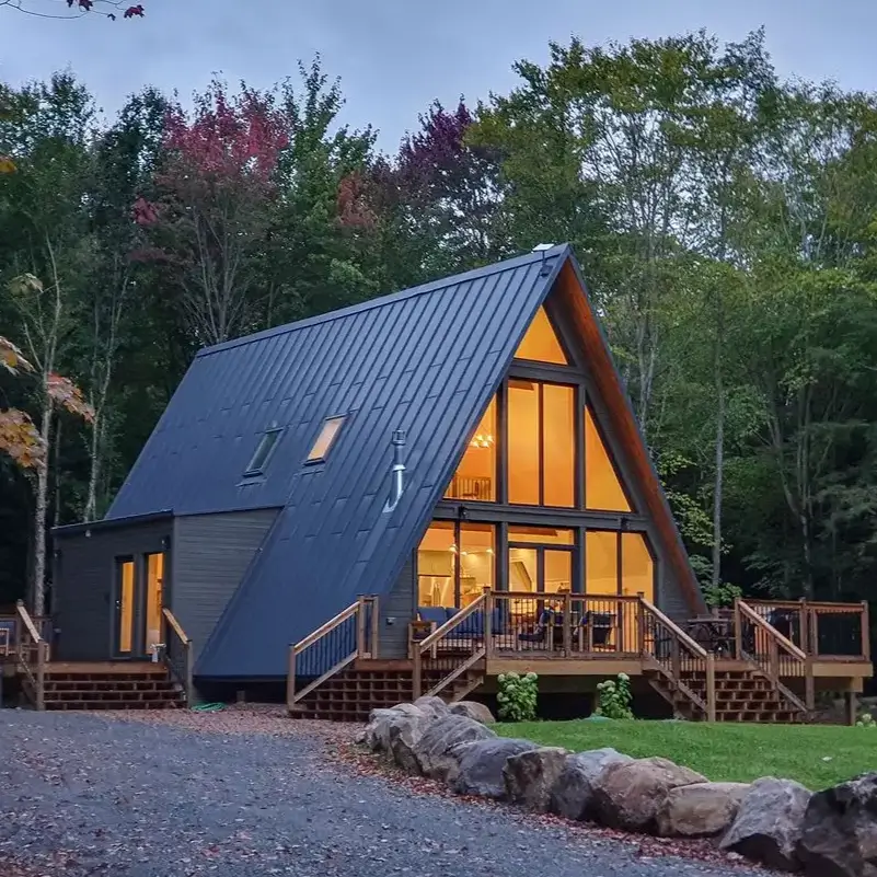 Large, contemporary Avrame A-frame house kit with a dark metal roof and expansive multi-level deck.