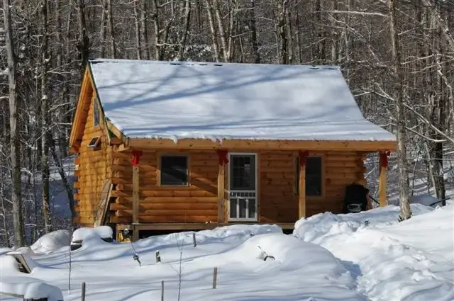 The Discoverer log cabin kit in a deep snowy forest, showing its authentic winter appeal.