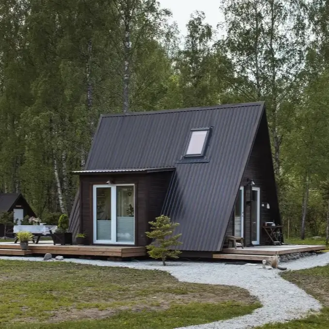 Avrame Duo 57 A-frame house kit, a compact modern design with a dark roof and surrounding greenery.