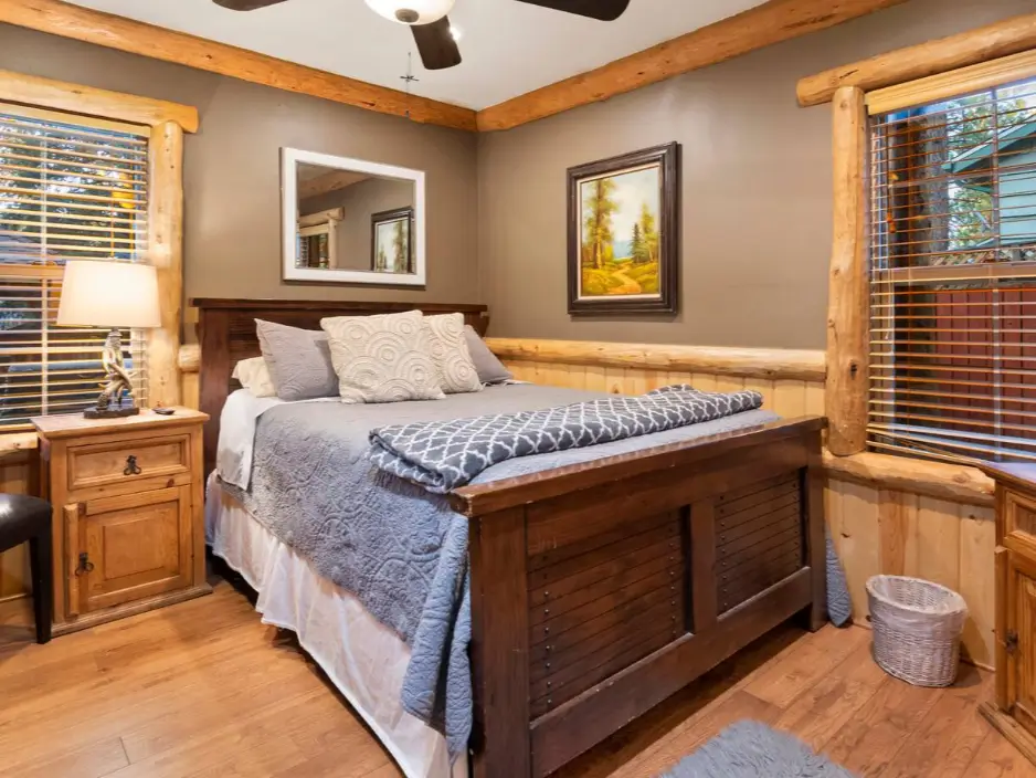 A serene and cozy log cabin bedroom in Big Bear with a dark wood bed and natural wainscoting.